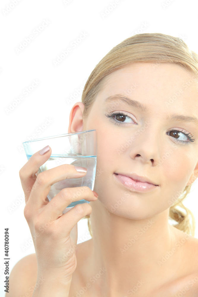Blond woman holding glass of water to face Blond woman holding glass of water to face