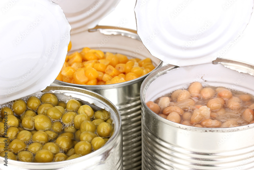 Open tin cans of corn, beans and peas isolated on white