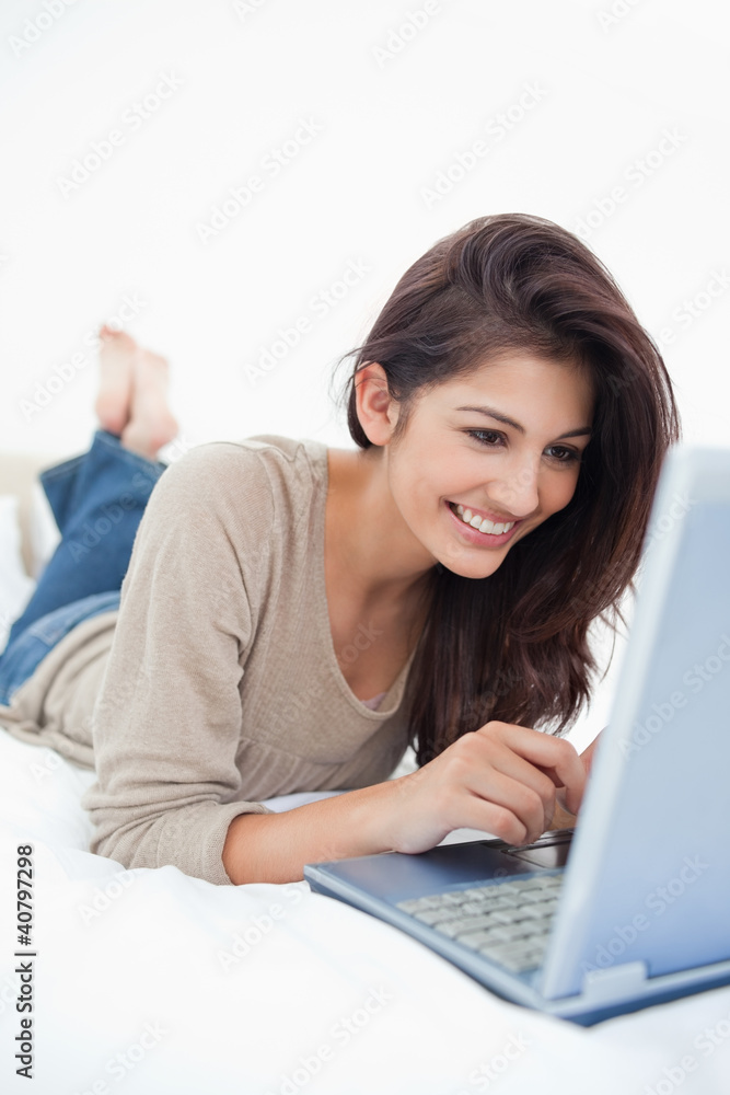 Close up, woman lying on the bed smiling with her laptop in fron Close up, woman lying on the bed smiling with her laptop in fron