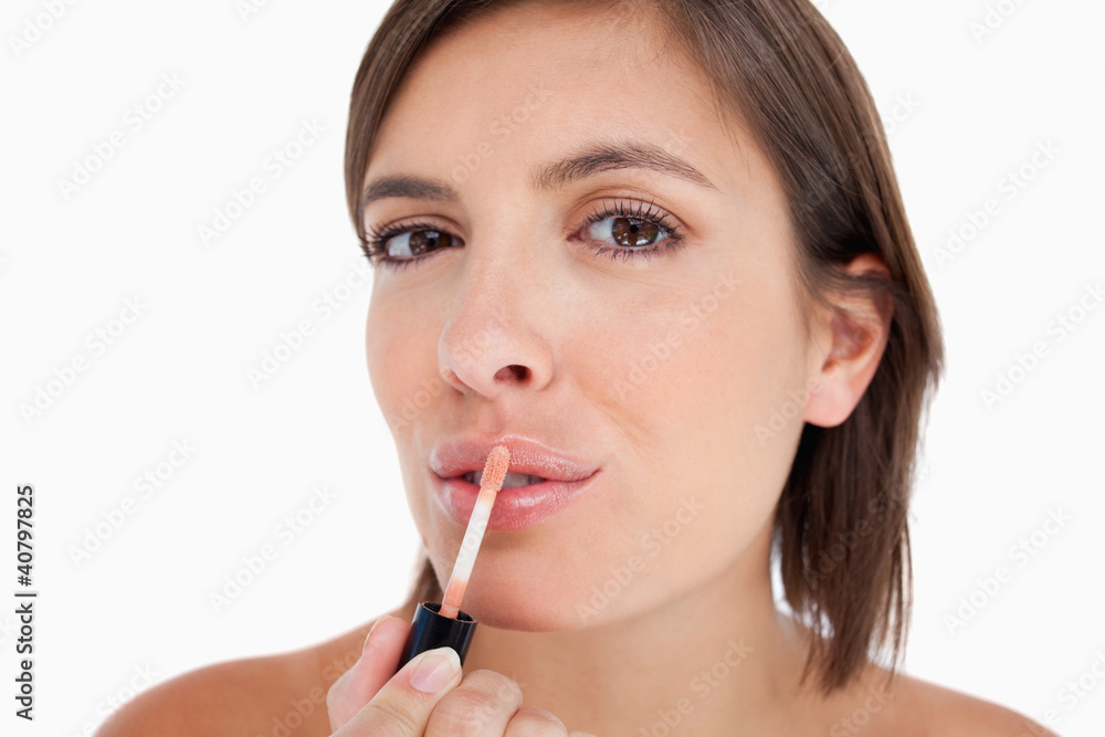 Young woman applying lip gloss with the brush included Young woman applying lip gloss with the brush included