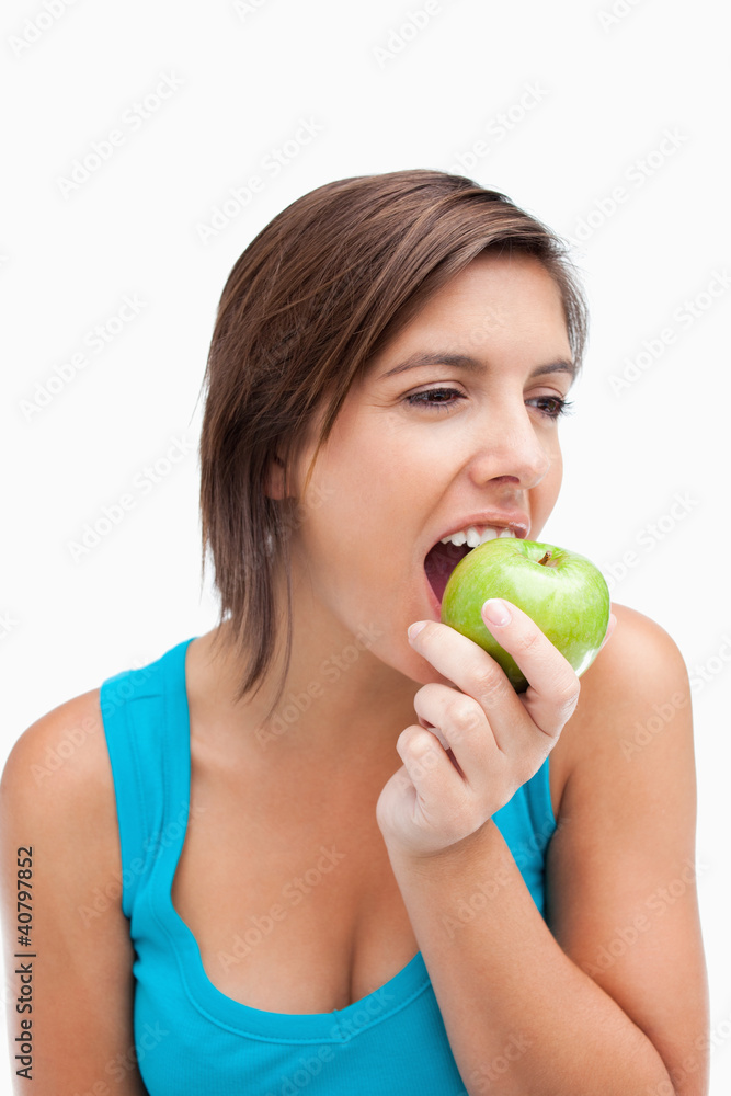 Teenager looking on the side while eating a green apple Teenager looking on the side while eating a green apple