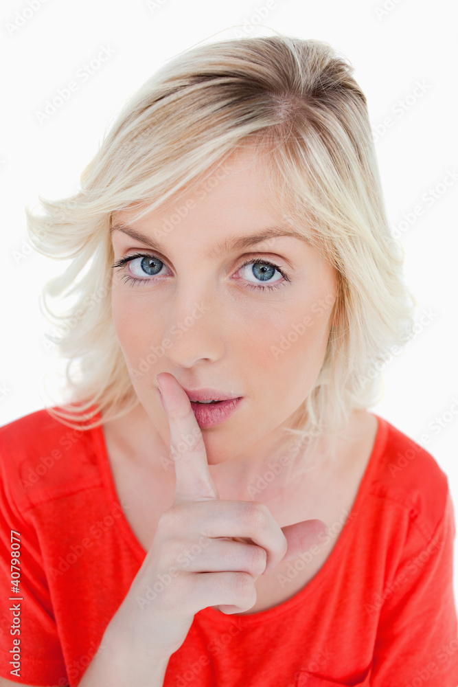 Young blonde woman telling to be quiet with her finger on her mo Young blonde woman telling to be quiet with her finger on her mo