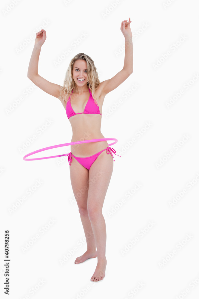 Smiling teenager playing hula-hoop with her arms raised Smiling teenager playing hula-hoop with her arms raised