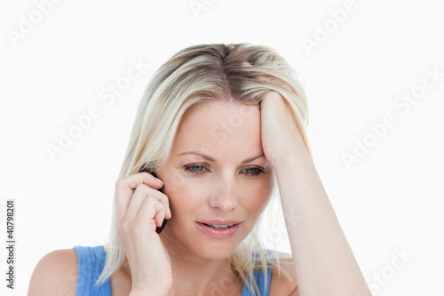 Serious woman talking on the phone with her hand on her forehead