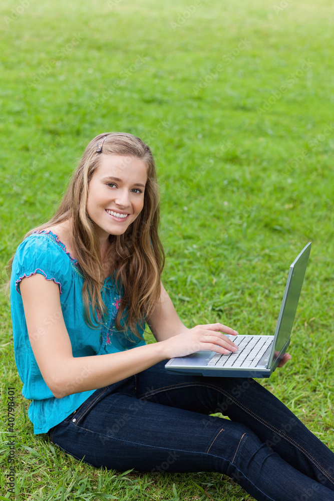 Young attractive girl looking at the camera while using her lapt Young attractive girl looking at the camera while using her lapt