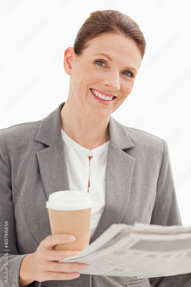 Smiling businesswoman holding newspaper and cup Smiling businesswoman holding newspaper and cup