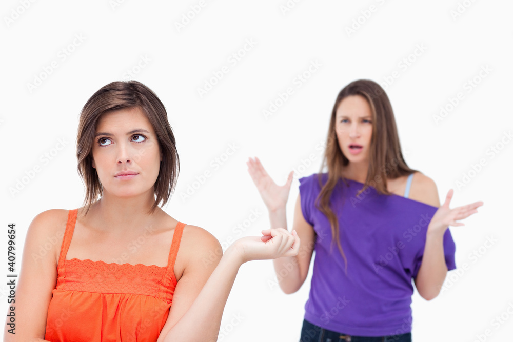 Exasperated teenager standing upright while her friend is roarin Exasperated teenager standing upright while her friend is roarin