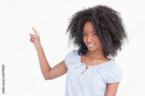 Smiling young woman pointing back side by finger