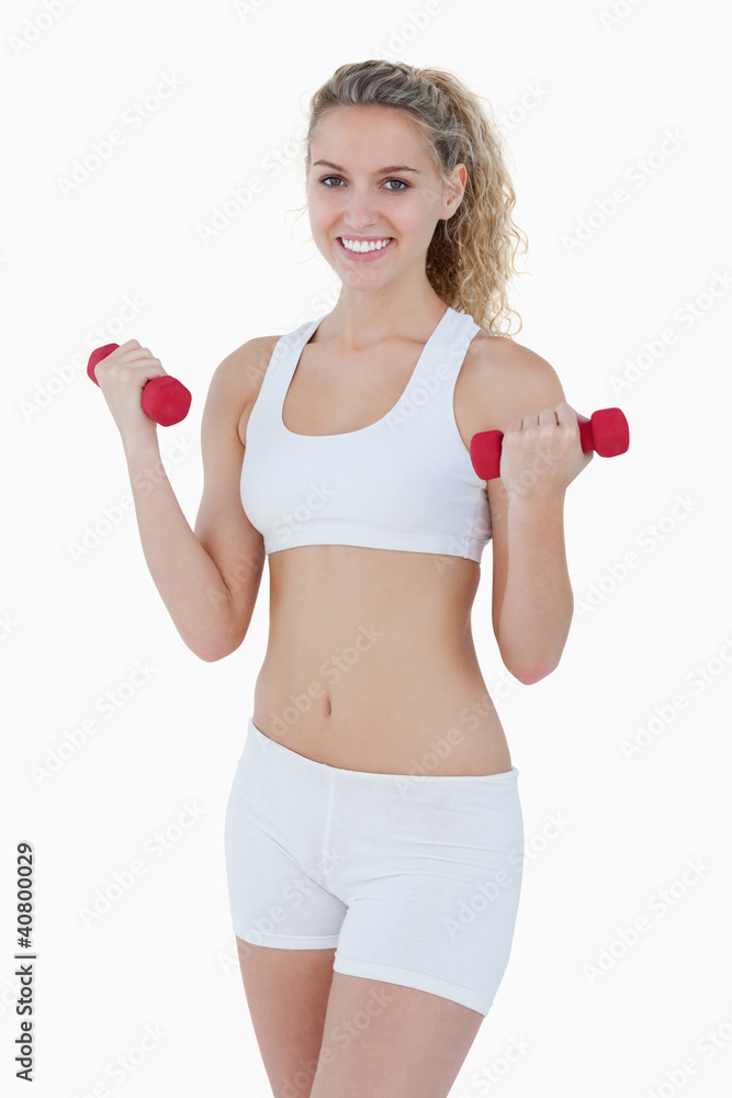 Young attractive woman smiling while lifting red weights Young attractive woman smiling while lifting red weights