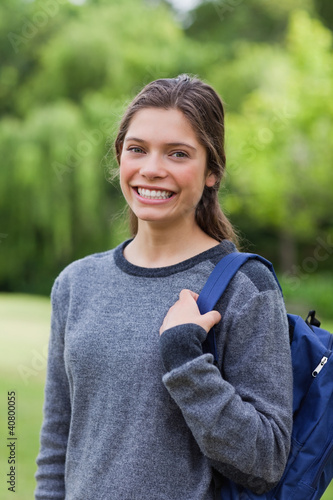 Young girl standing up with hair tied while carrying her backpac