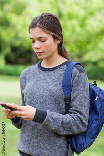 Young serious girl sending a text while standing in the countrys