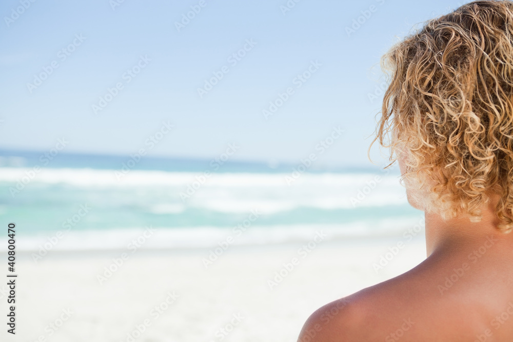 Young blonde man looking at the sea while sunbathing Young blonde man looking at the sea while sunbathing