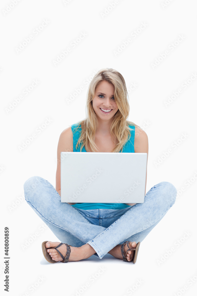 A young woman is sitting on the ground with a laptop A young woman is sitting on the ground with a laptop