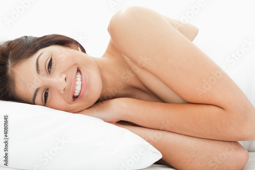 A woman is lying on the bed, her head is resting on the pillow w