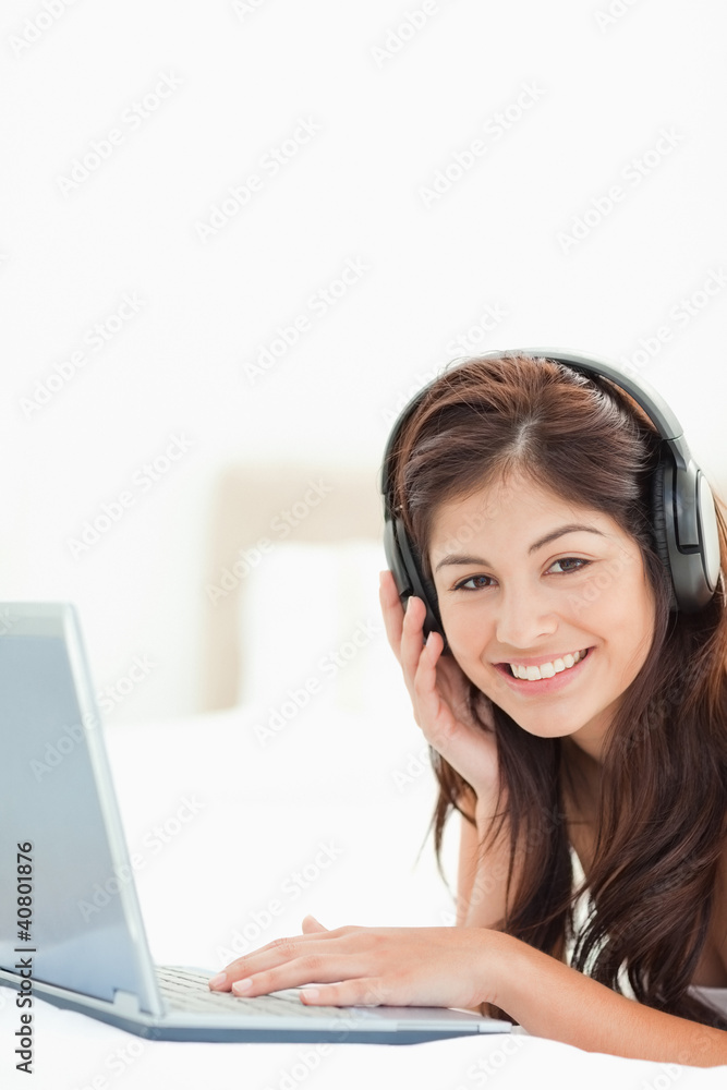 Close up, woman using headphones and laptop on a bed Close up, woman using headphones and laptop on a bed