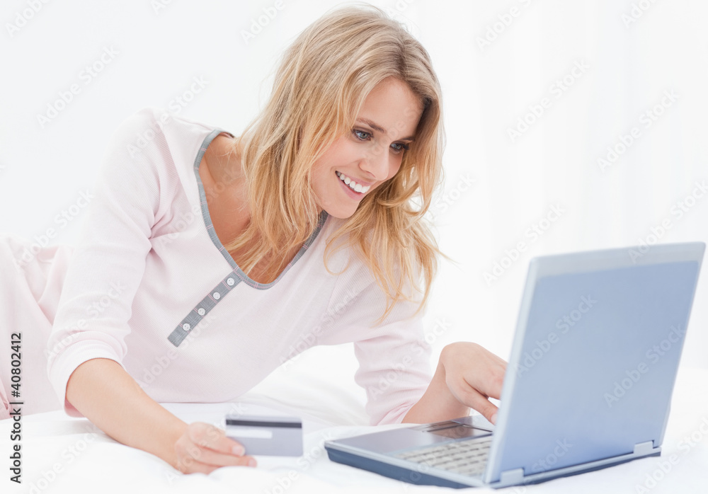 Woman smiling using her credit card and laptop to order online Woman smiling using her credit card and laptop to order online