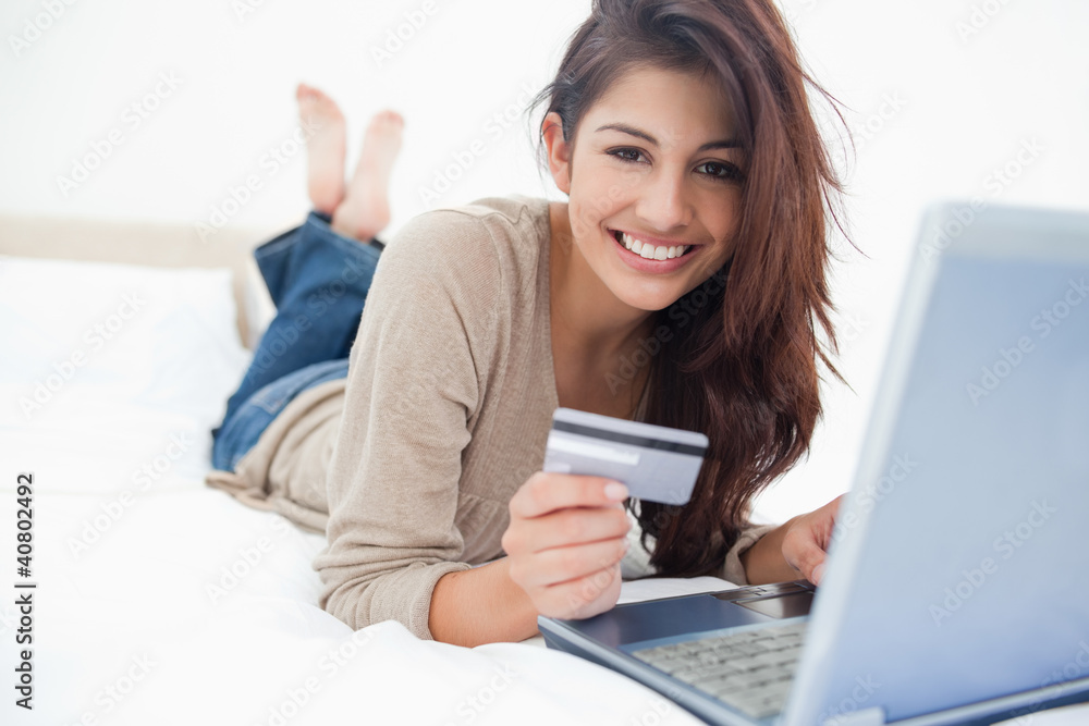 Woman smiling and looking ahead as she uses her laptop, and cred Woman smiling and looking ahead as she uses her laptop, and cred