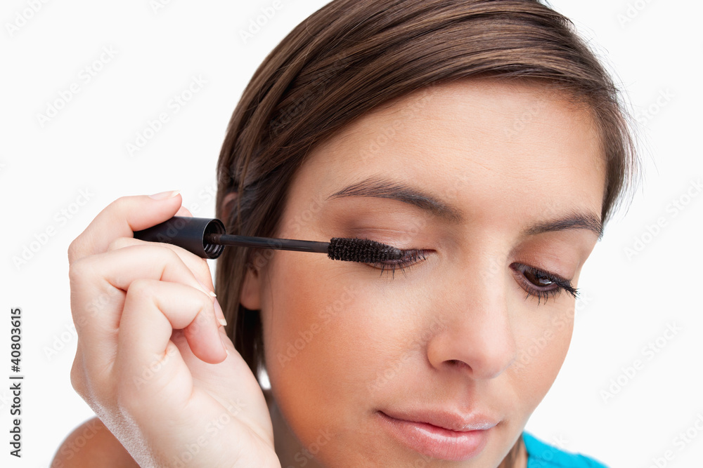 Relaxed teenager carefully applying her mascara on her eye