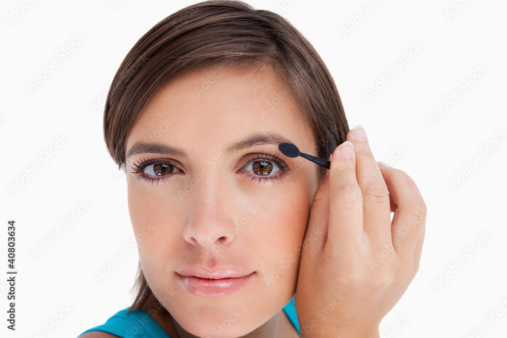 Young woman looking at the camera putting eyeshadow on her eyeli Young woman looking at the camera putting eyeshadow on her eyeli