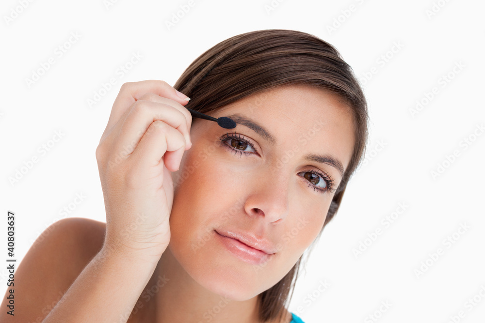 Beautiful teenager leaning her head while applying eyeshadow