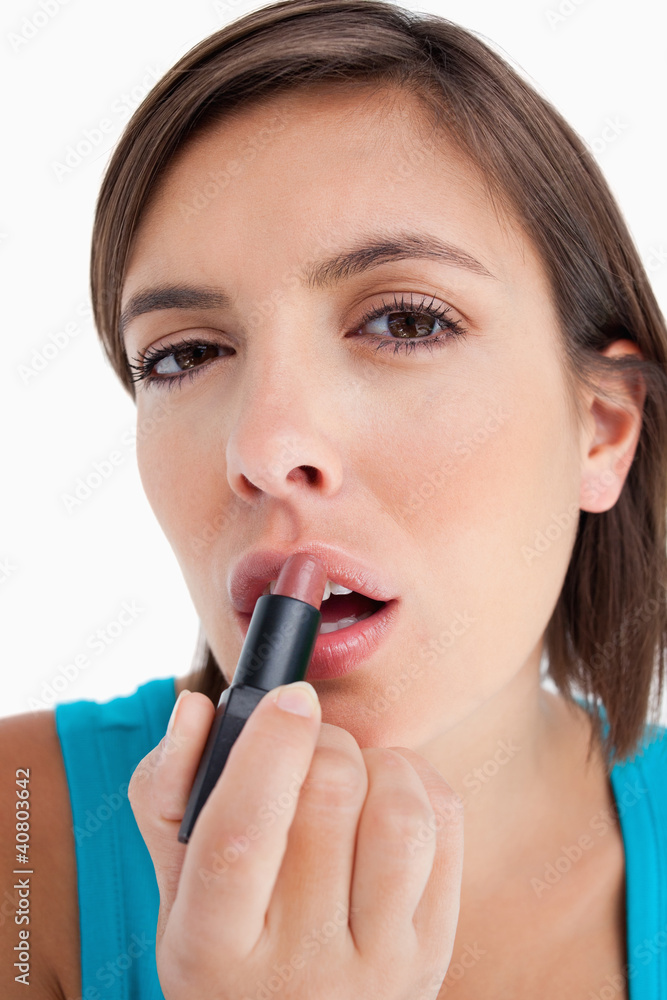 Attractive teenager applying lipstick against a white background Attractive teenager applying lipstick against a white background