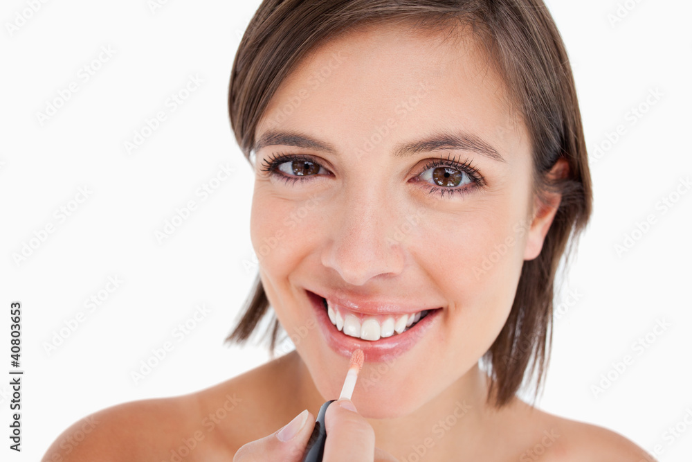 Teenager smiling while applying lip gloss with a lip brush Teenager smiling while applying lip gloss with a lip brush