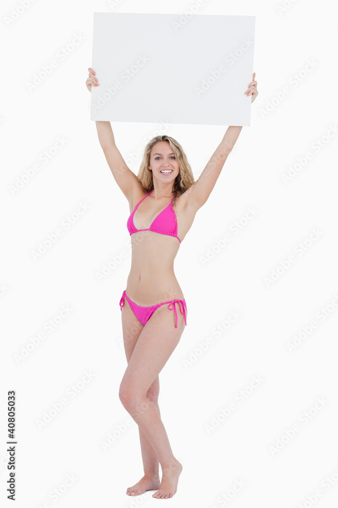 Young blonde woman raising a blank poster above her head Young blonde woman raising a blank poster above her head
