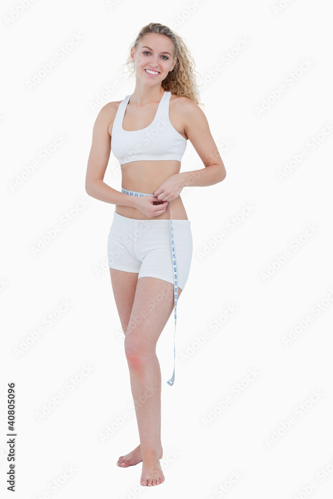 Smiling teenager using a measuring tape for her waist Smiling teenager using a measuring tape for her waist