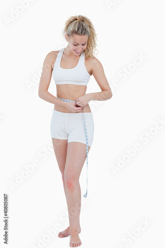 Young attractive woman measuring her waist