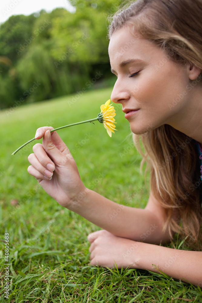 Young calm woman closing her eyes while smelling a yellow flower Young calm woman closing her eyes while smelling a yellow flower