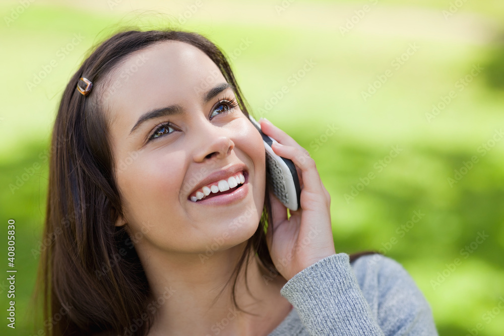 Young smiling woman looking up while talking on the phone Young smiling woman looking up while talking on the phone