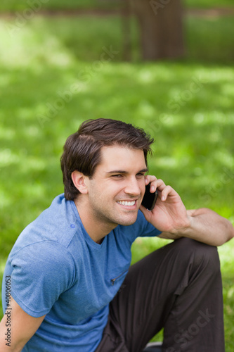 Young smiling man calling with his cellphone while sitting in a
