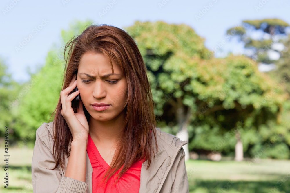 Woman looking towards the ground while on the phone in a bright Woman looking towards the ground while on the phone in a bright