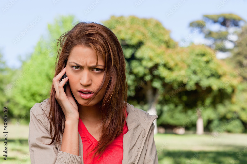 Woman with a serious expression talking on the phone in a bright Woman with a serious expression talking on the phone in a bright