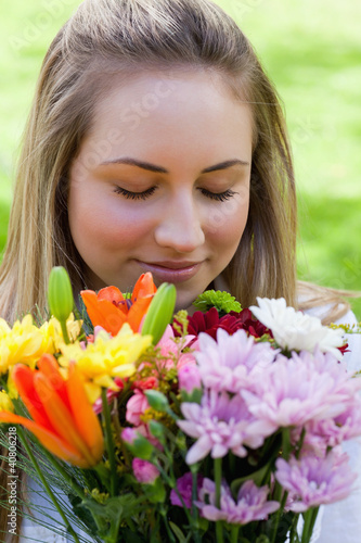 Young blonde girl closing her eyes while smelling a bunch of flo