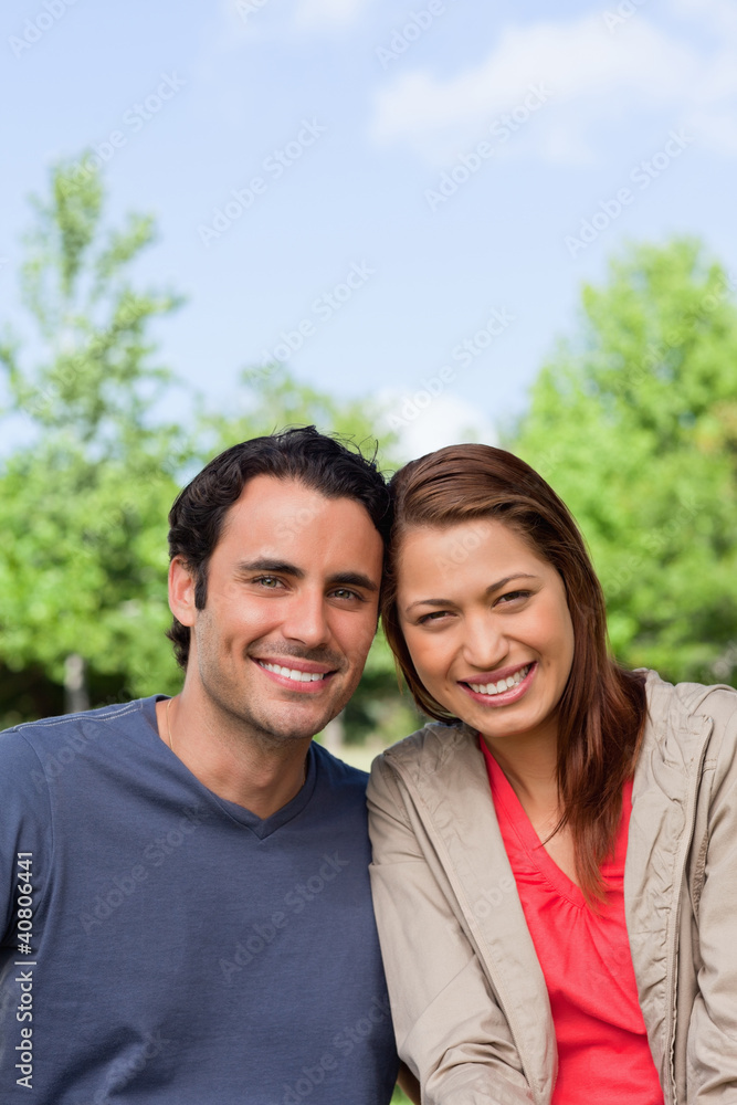 Two friends smiling as the look ahead while leaning against each