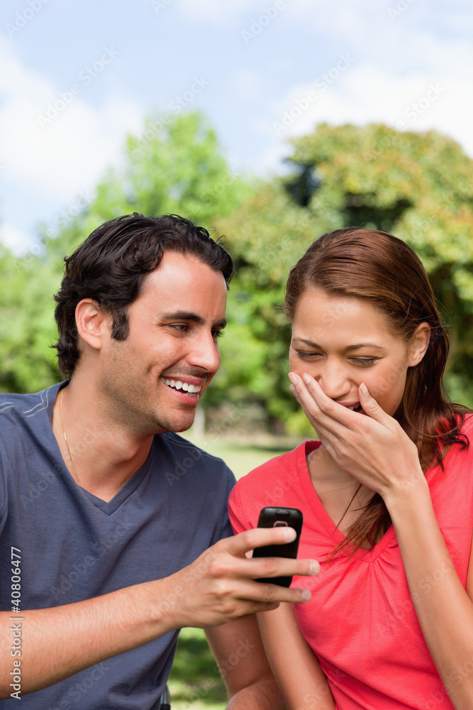 Woman aughing at something being shown to her on her friend's ph Woman aughing at something being shown to her on her friend's ph