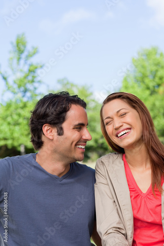 Man looking his friend as she is laughing joyfully while sitting