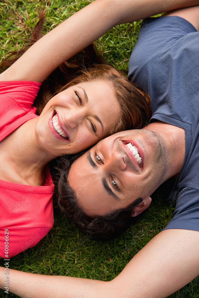 Two friends smiling while lying head to shoulder with an arm out Two friends smiling while lying head to shoulder with an arm out