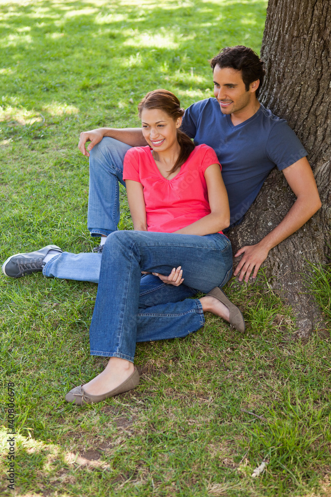 Two friends sitting together against a tree Two friends sitting together against a tree