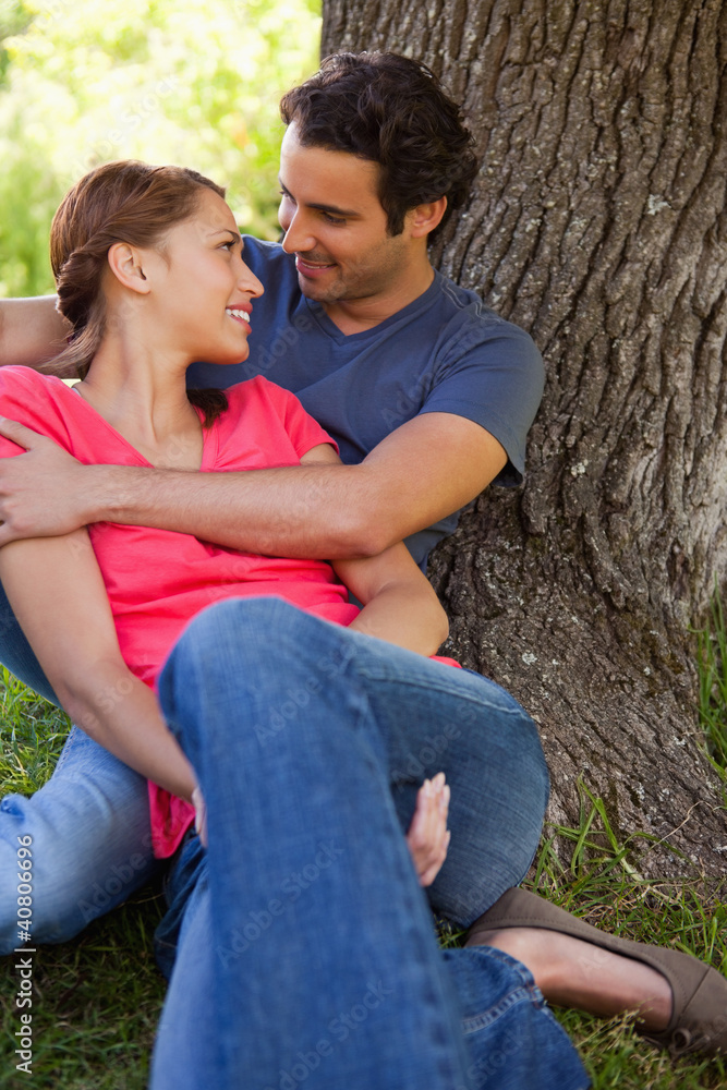 Man looking at his friend as he holds her while they sit togethe Man looking at his friend as he holds her while they sit togethe