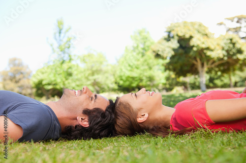 Two smiling friends looking upwards while lying head to head