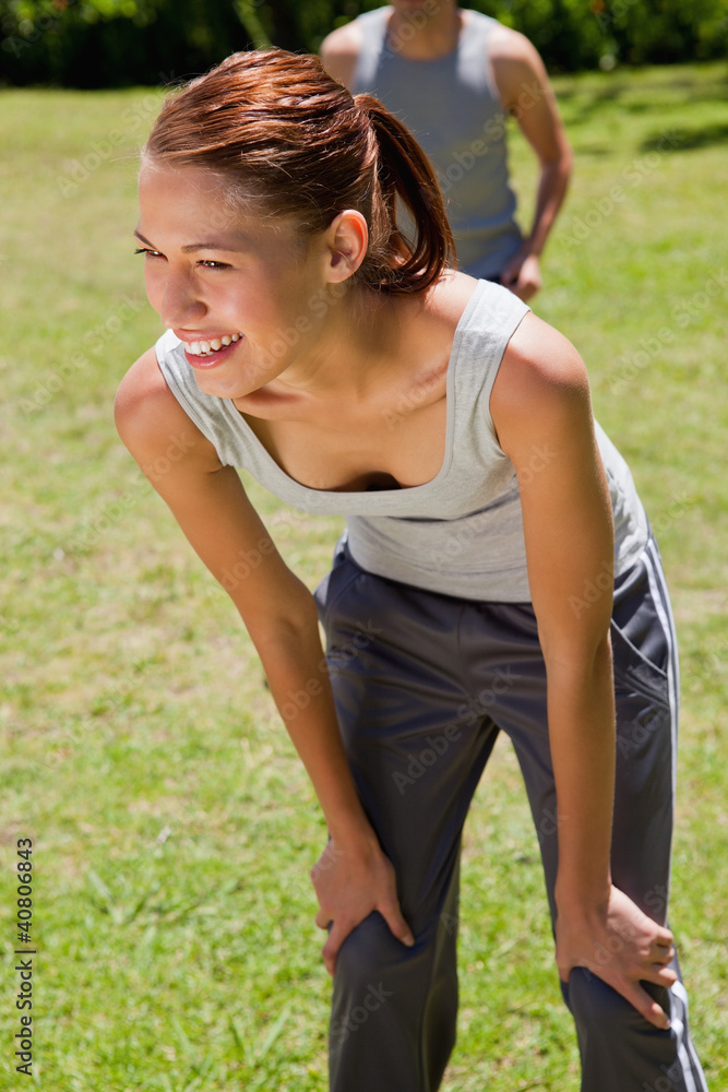 Smiling woman bending over while a man is walkng behind her