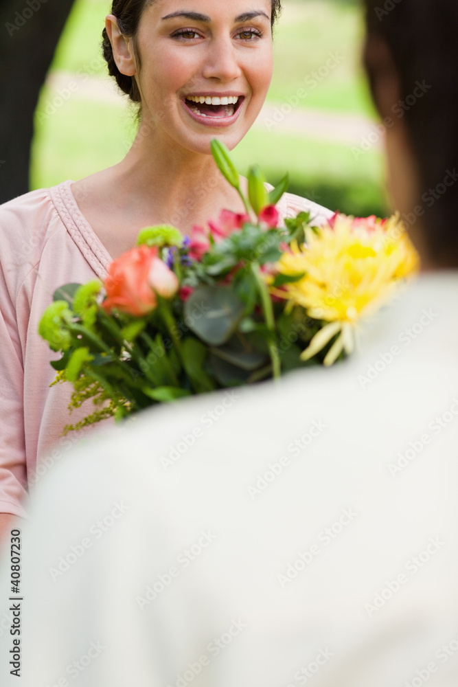 Woman laughing as she is being presented with flowers Woman laughing as she is being presented with flowers