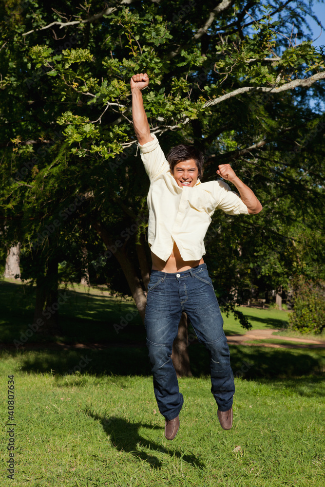 Man jumping with his arms raised as he rejoices Man jumping with his arms raised as he rejoices
