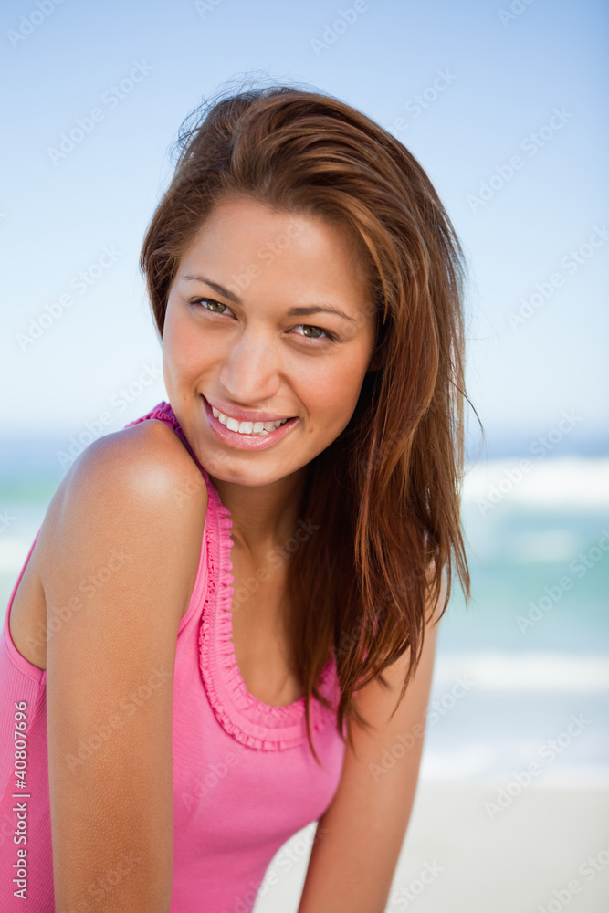 Young smiling woman standing in front of the sea while turning h