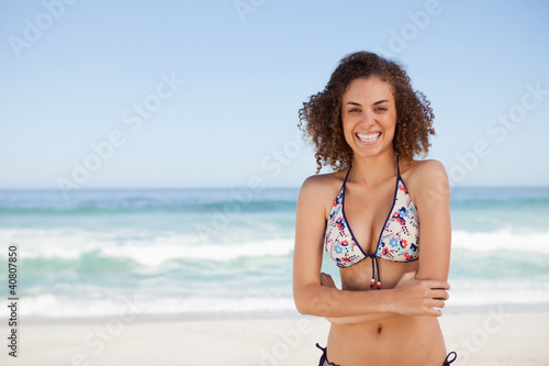 Young smiling woman standing in front of the sea with arms cross