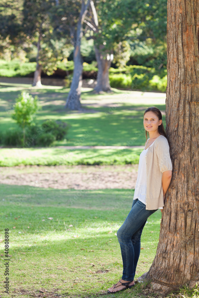 Naklejka premium Woman in the countryside leaning against a tree