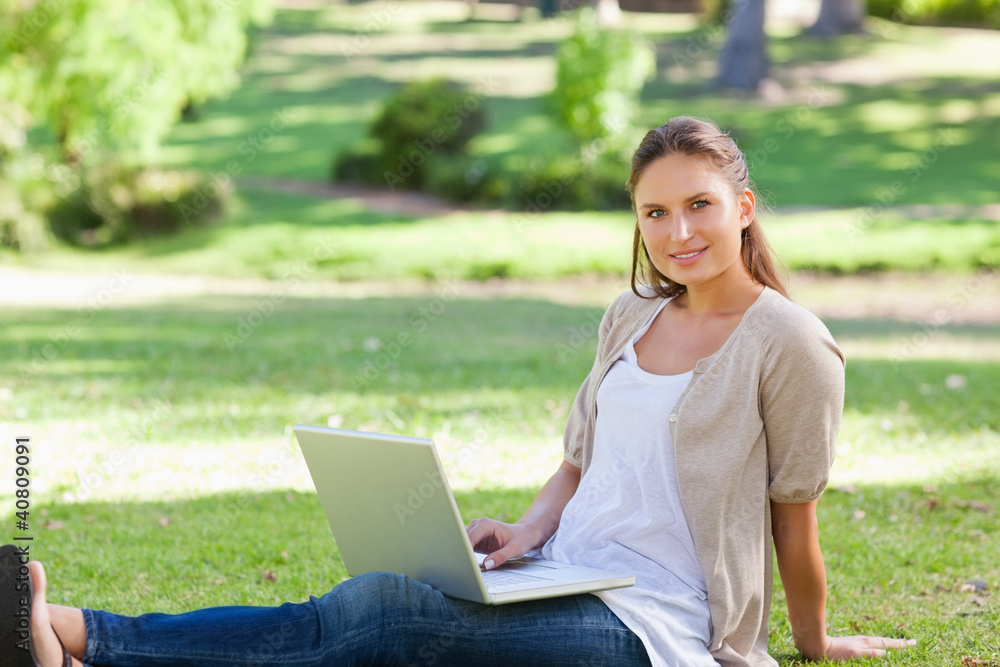 Woman with her laptop sitting on the lawn Woman with her laptop sitting on the lawn