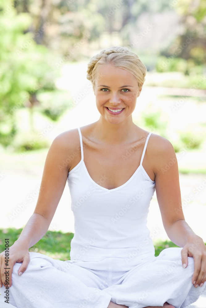 Smiling woman in a yoga position on the lawn
